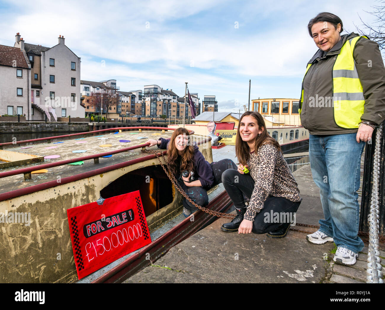 Leith, Edimburgo, Escocia, Reino Unido, 8 de noviembre de 2018. Intervención artística en la Comunidad: Leith Escuela de Arte Estudiantes crean un pastiche de arte de Damien Hirst por decorar una casa flotante descuidados con los círculos de color, refiriéndose a Hirst manchas de pinturas, fotos de un tiburón en referencia a su famoso tiburón conservado ilustraciones y un recorte de la artista. La intervención también se refiere a la renovación de una casa flotante del Támesis por Hirst y su esposa costando miles de libras. Este es uno de los varios sitios de intervención en Leith Foto de stock