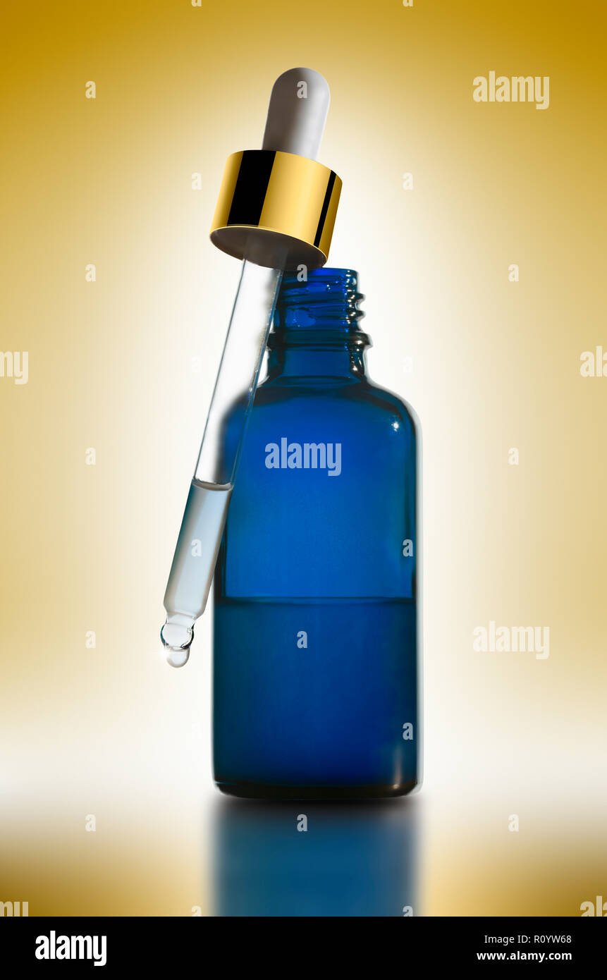 Tratamiento de belleza Esencial en botella con pipeta cuentagotas azul contra un fondo de color amarillo, studio bodegón Foto de stock