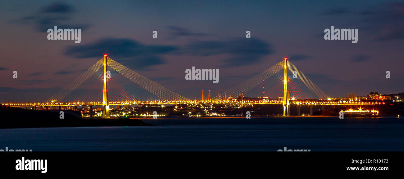 Una escena nocturna. Panorama de la Federación de puente que une la tierra firme y la isla rusa de Vladivostok. Foto de stock