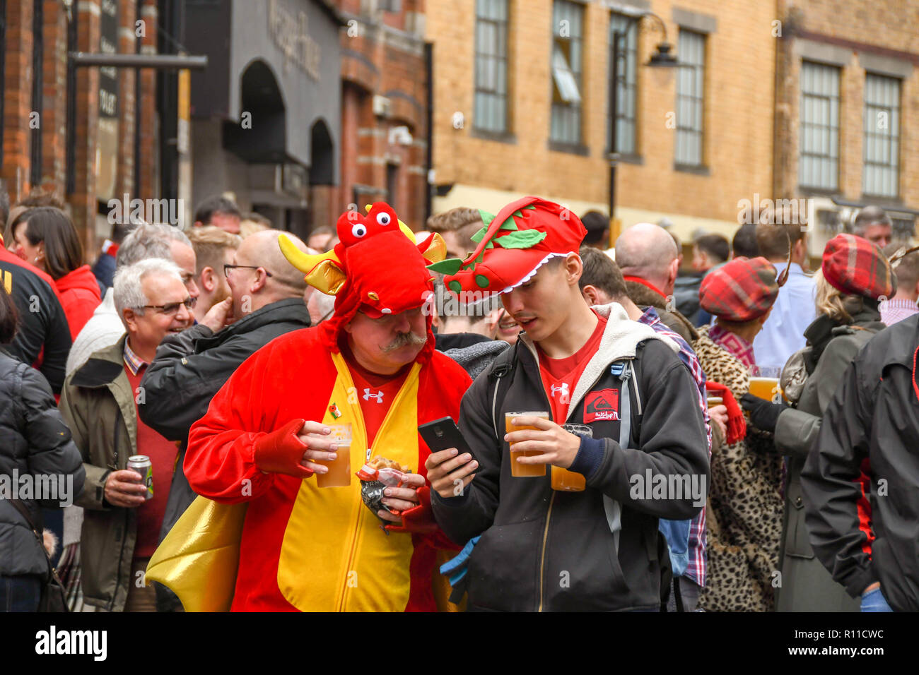 CARDIFF, GALES - 2018 DE NOVIEMBRE: Dos partidarios del rugby galés bebiendo y hablando en una multitud frente a un pub en el centro de Cardiff antes de un partido Foto de stock