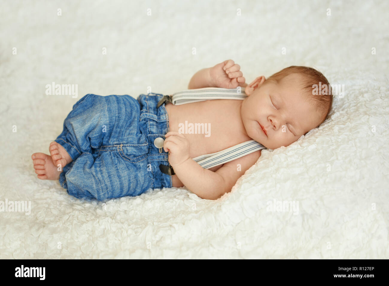 La moda en jeans de bebé recién nacido duerme en la cama. Moda para Fotografía de stock Alamy