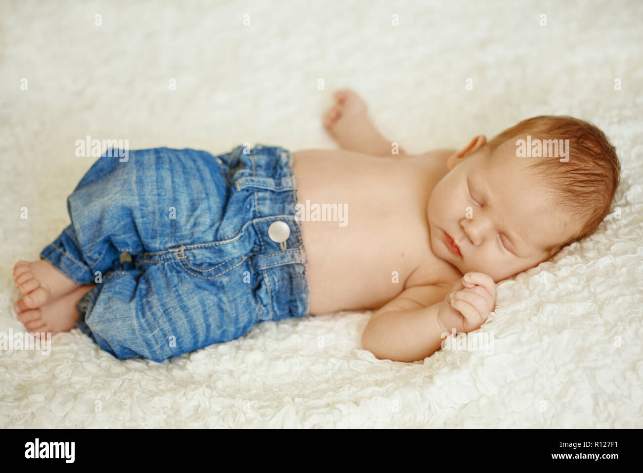 La moda en jeans de bebé recién nacido duerme en la cama. Moda para Fotografía de stock Alamy