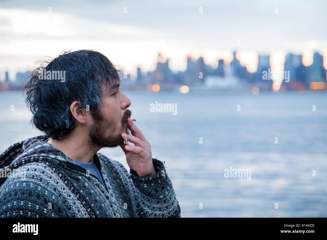 Un hombre joven fumar un porro con el centro de Vancouver, BC, en el contexto canadiense, poco después de la legalización de la marihuana. Foto de stock