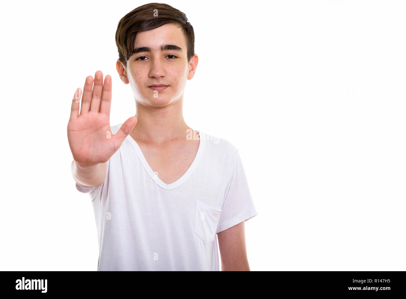 Foto de estudio de joven apuesto adolescente persa con parada de mano Foto de stock