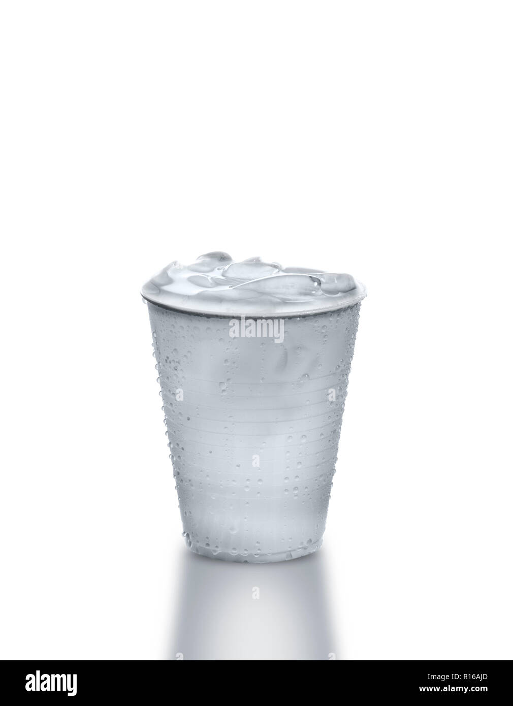 Vaso de plástico lleno de agua helada contra el fondo blanco. Foto de stock