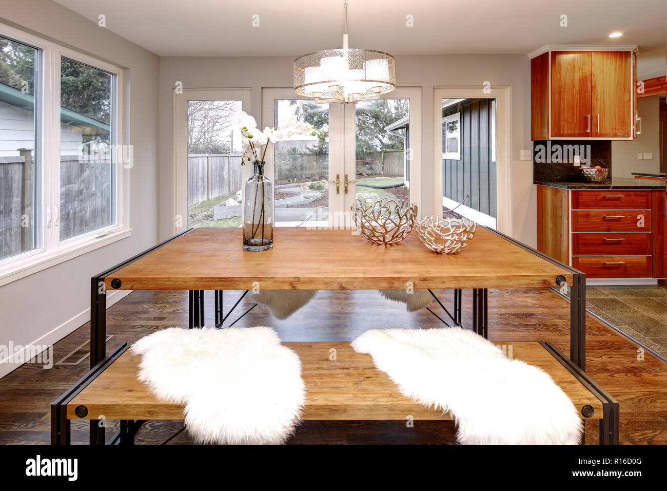 Amplio comedor con mesa de comedor de madera y puertas francesas que dan a la parte de atrás del jardín. Foto de stock