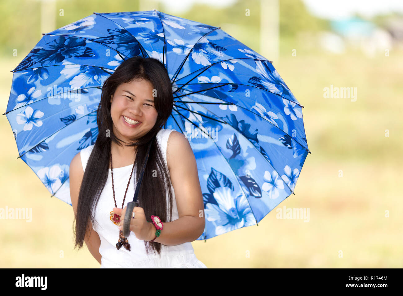 religión Alienación afijo Hermosa niña tailandesa bajo una sombrilla azul o paraguas para protegerla  contra el caliente sol del verano sonriente, feliz en la cámara Fotografía  de stock - Alamy
