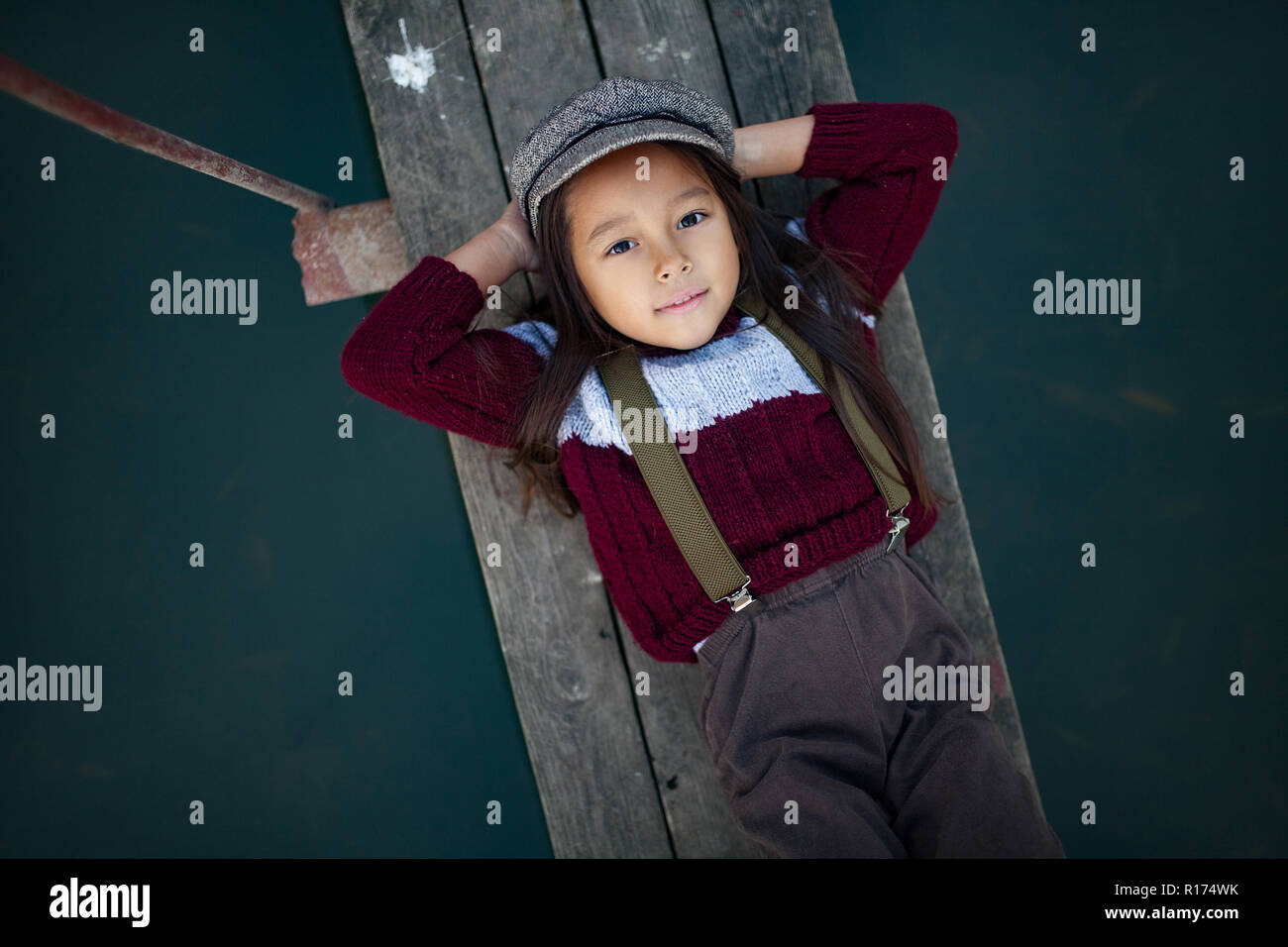 Niño Niña en la tapa se encuentra el puente de madera y sonrisas en el fondo de río. Vista desde arriba. Closeup. Foto de stock