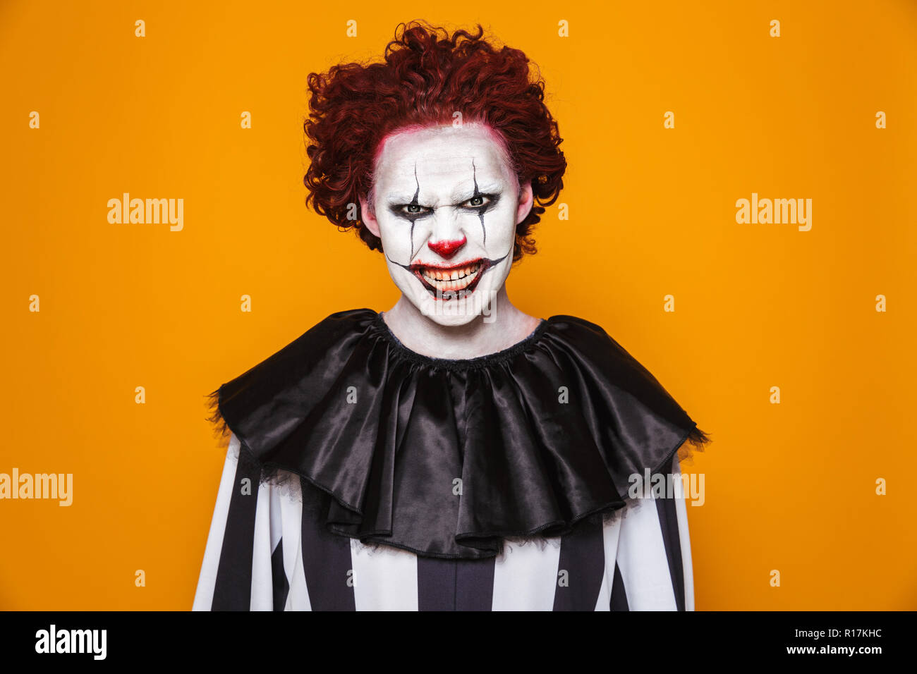 Enojado el hombre payaso 20s vestidos de traje negro y el maquillaje de  halloween mirando a la cámara aislada sobre fondo amarillo Fotografía de  stock - Alamy