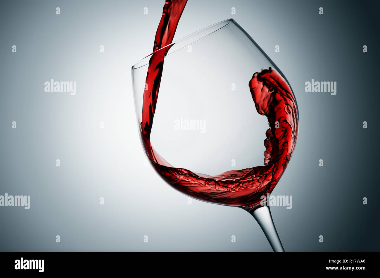 Verter en el vaso de vino tinto, fondo gris Foto de stock
