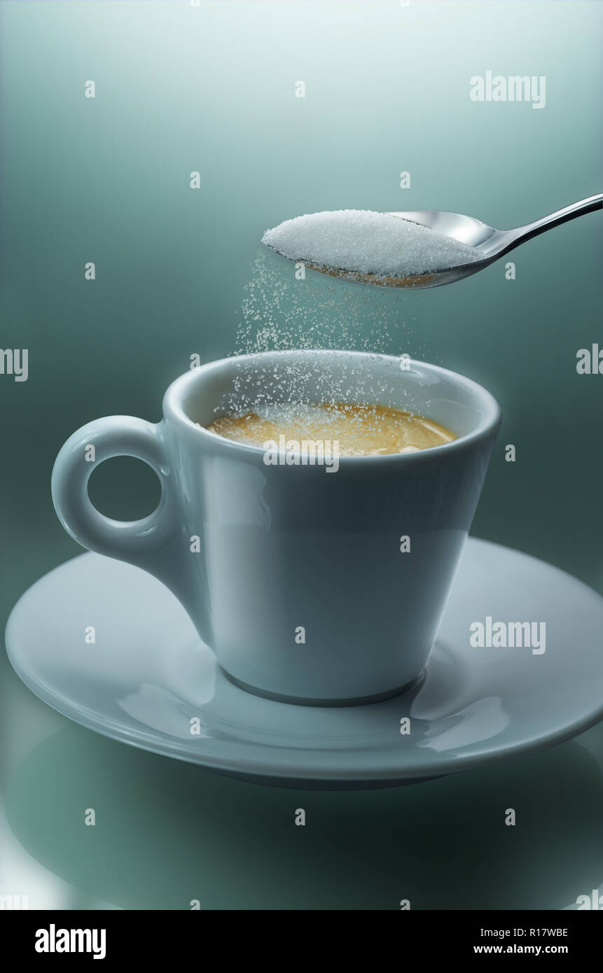 Verter el azúcar de cucharada en una taza de café, fondo liso Foto de stock
