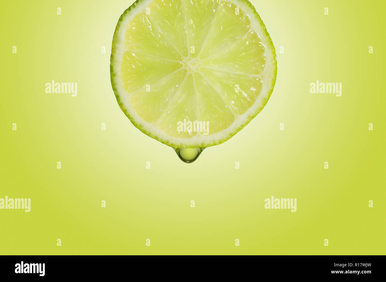 Vista cercana de la rodaja de limón con gota de zumo, fondo verde Foto de stock