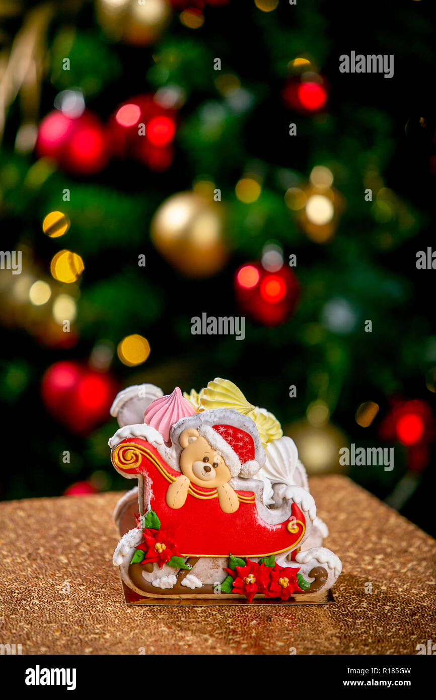 Gingerbread trineo con osito de peluche delante de desenfoque de Chrismtas luces adornado abeto. Vacaciones dulces. Tema de Navidad y Año Nuevo. Fiestas Foto de stock