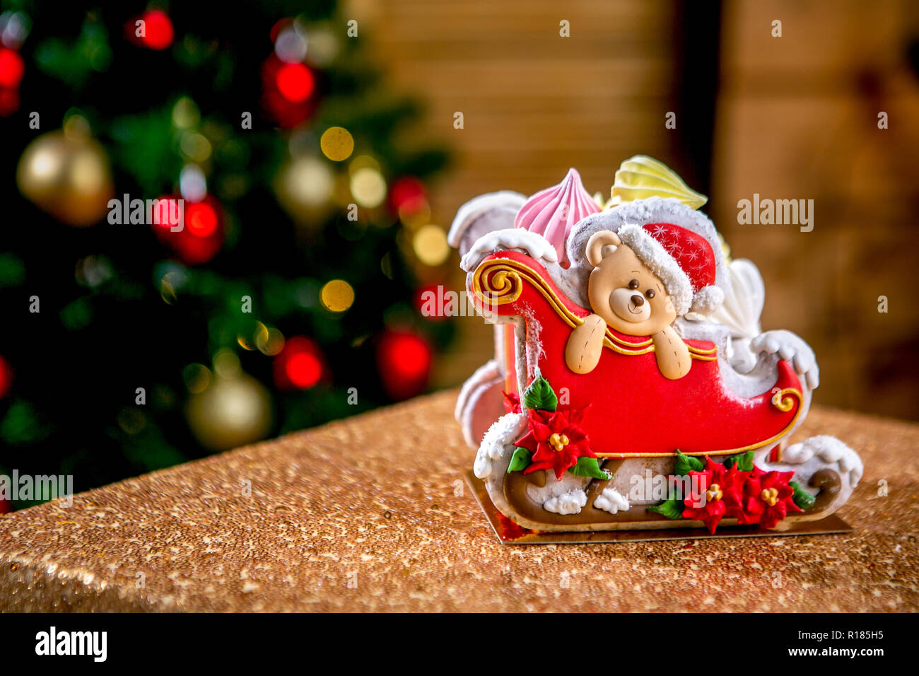 Gingerbread trineo con osito de peluche delante de desenfoque de Chrismtas luces adornado abeto. Vacaciones dulces. Tema de Navidad y Año Nuevo. Fiestas Foto de stock