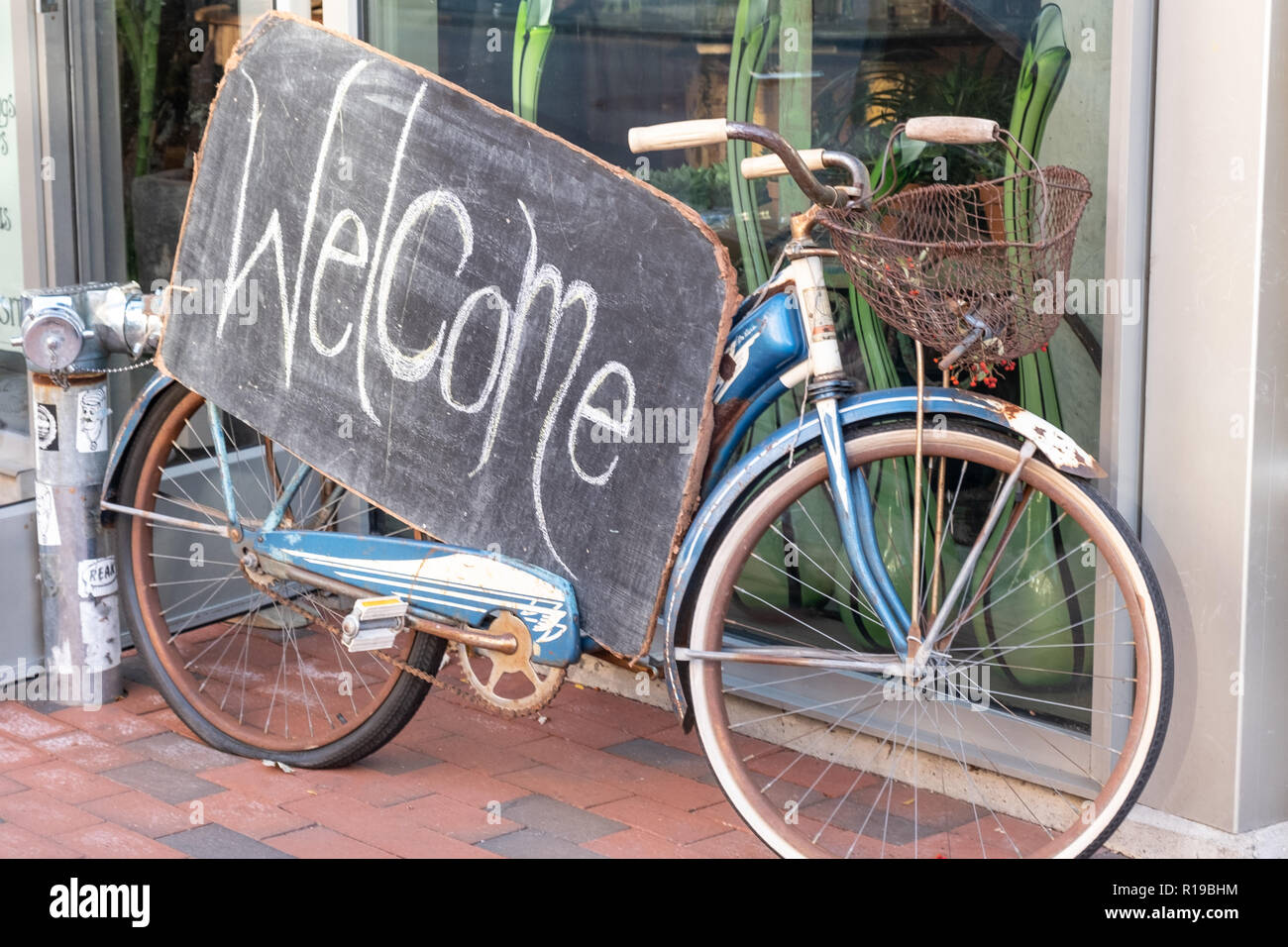 Una bicicleta con un cartel de bienvenida en frente de una tienda en Harvard Square Foto de stock