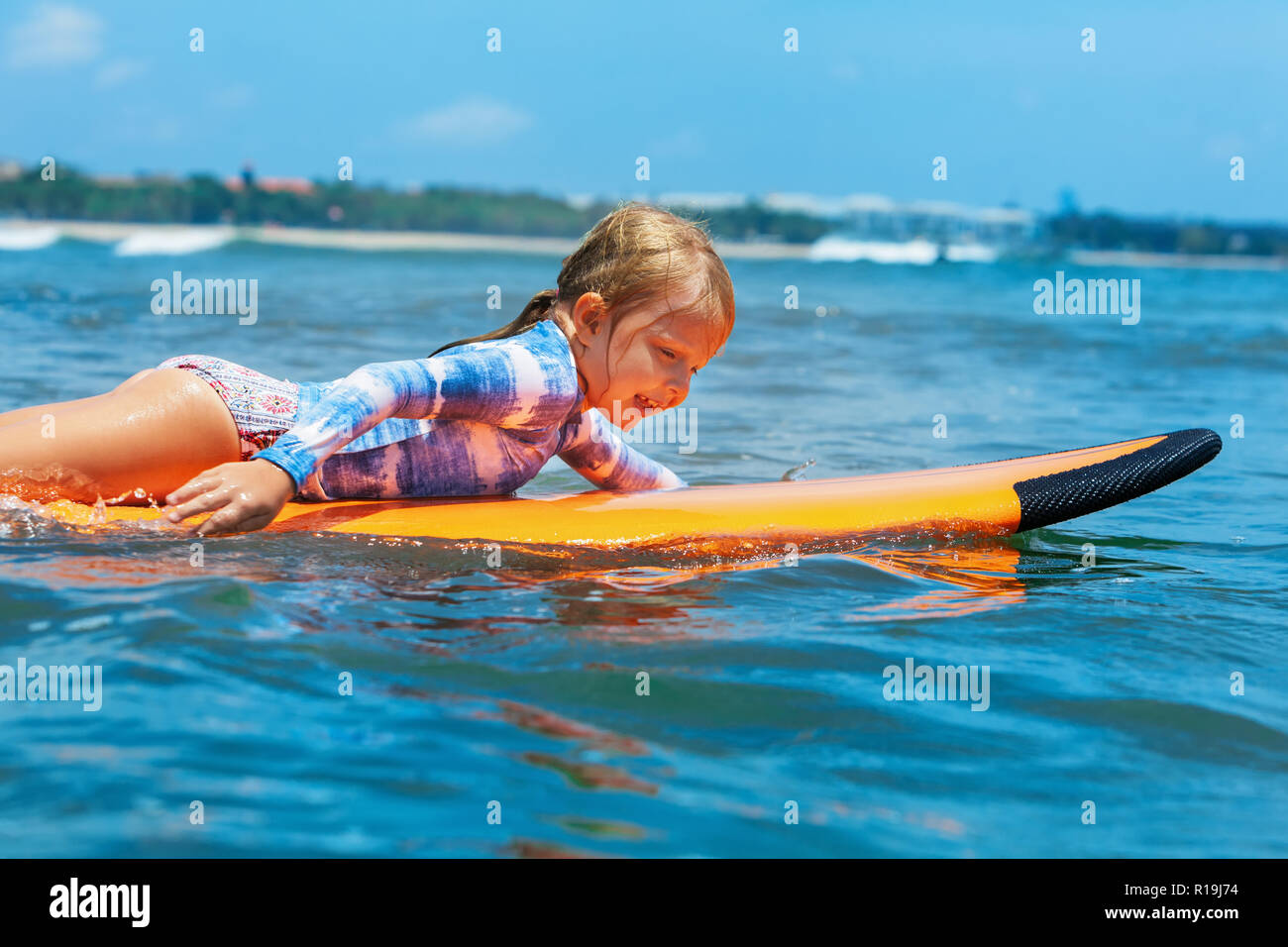 Niña feliz - joven surfista de paddle surf con la diversión en las olas del mar. Familia activo estilo de vida al aire libre para niños, deportes acuáticos, natación actividad lecciones Foto de stock