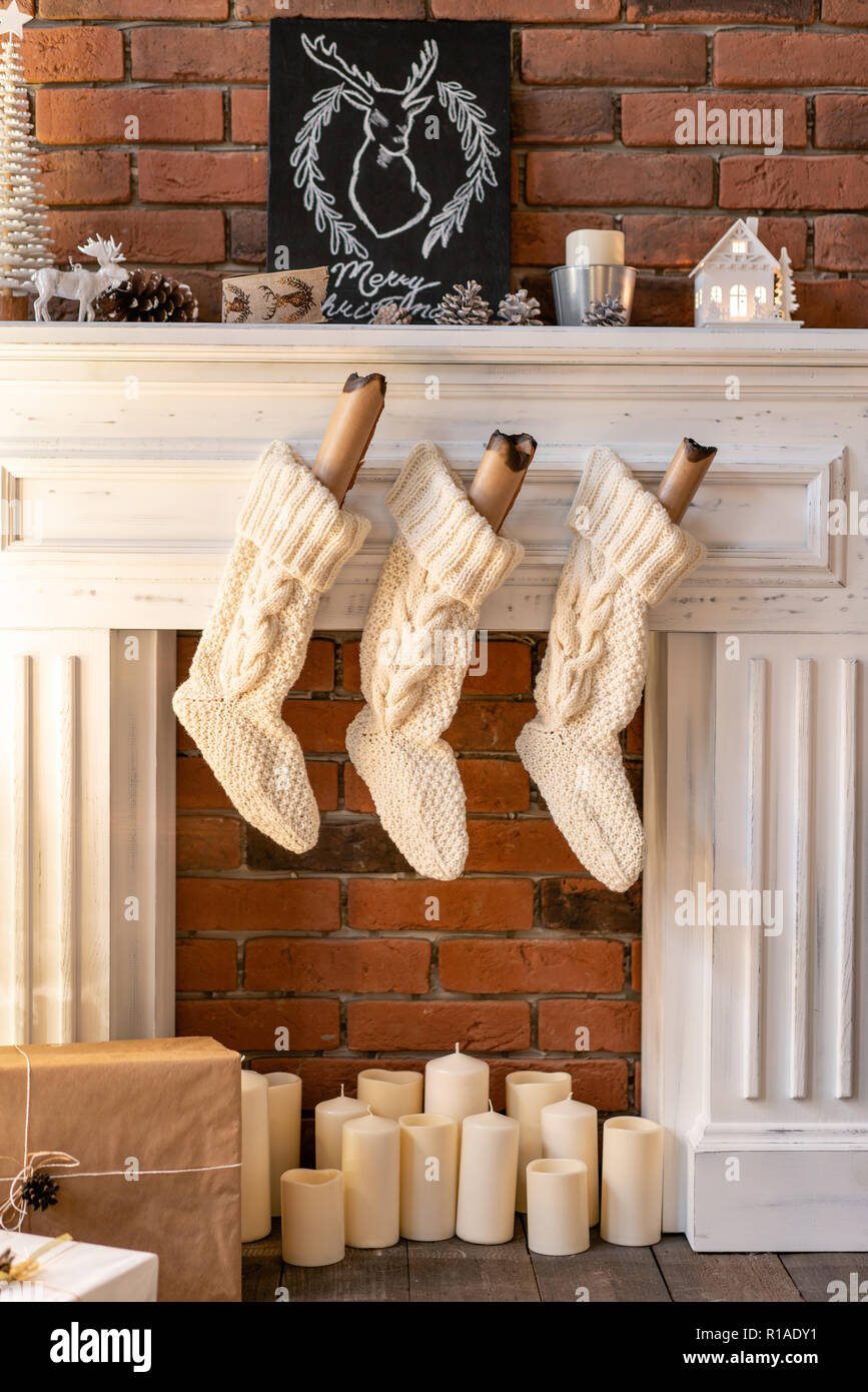 Calcetines de lana blanca de Santa en la hoguera. Apartamentos tipo loft,  pared de ladrillo con velas y corona del árbol de Navidad Fotografía de  stock - Alamy