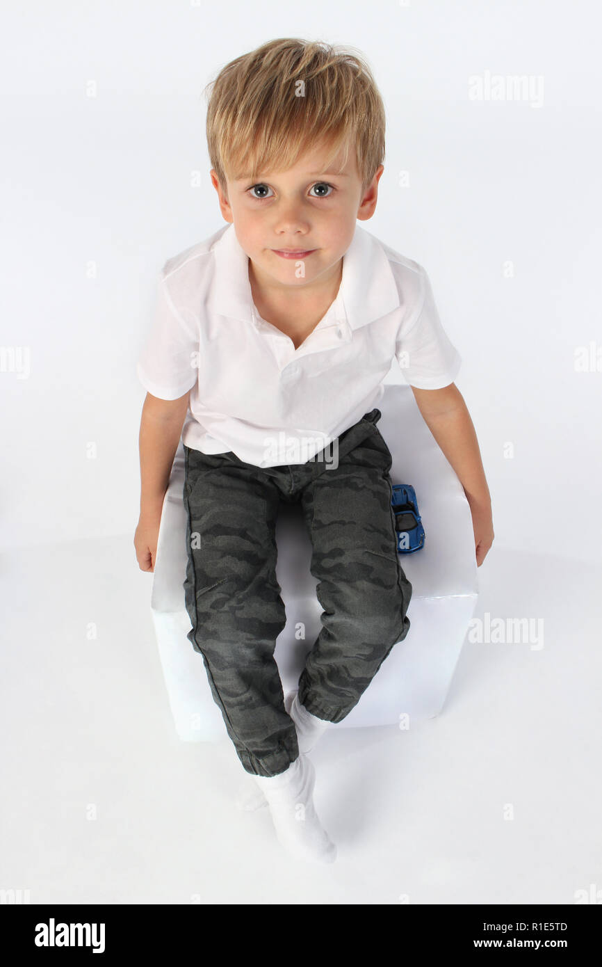 Adorable muchacho sentado en un cubo gigante de papel y elevando su cabeza hacia arriba Foto de stock