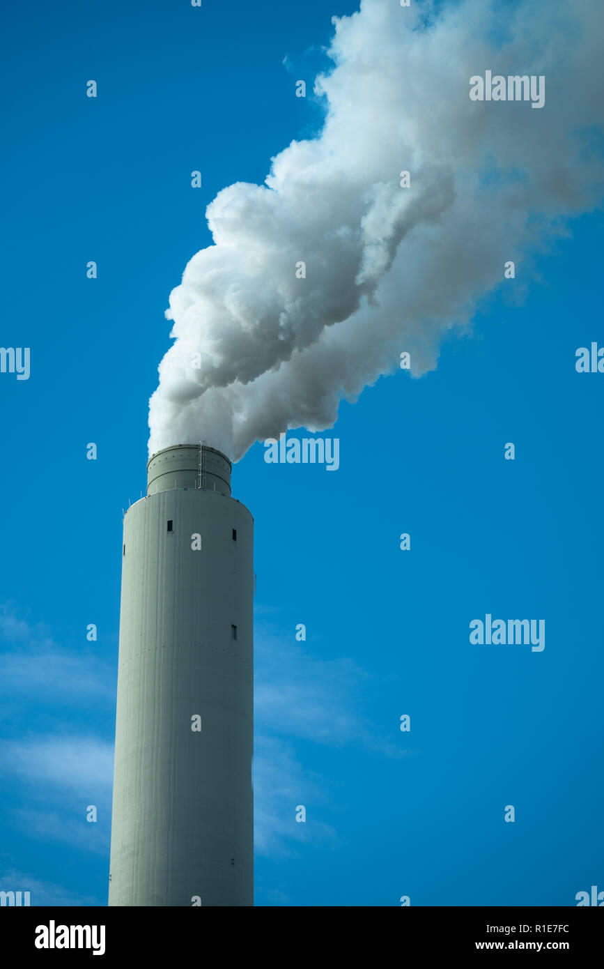 Orientación vertical de pila de humo humo blanco contra el cielo azul Foto de stock