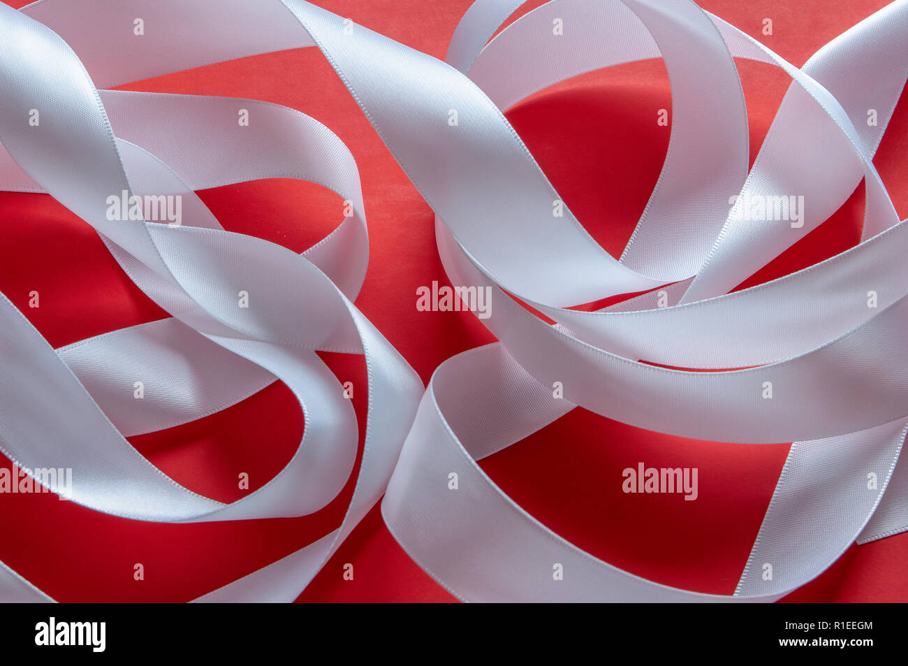 Un continuo remolino de anchura media cinta de satén blanco brillante  contra un lentamente graduada de fondo de papel rojo liso en un formato de  imagen horizontal Fotografía de stock - Alamy