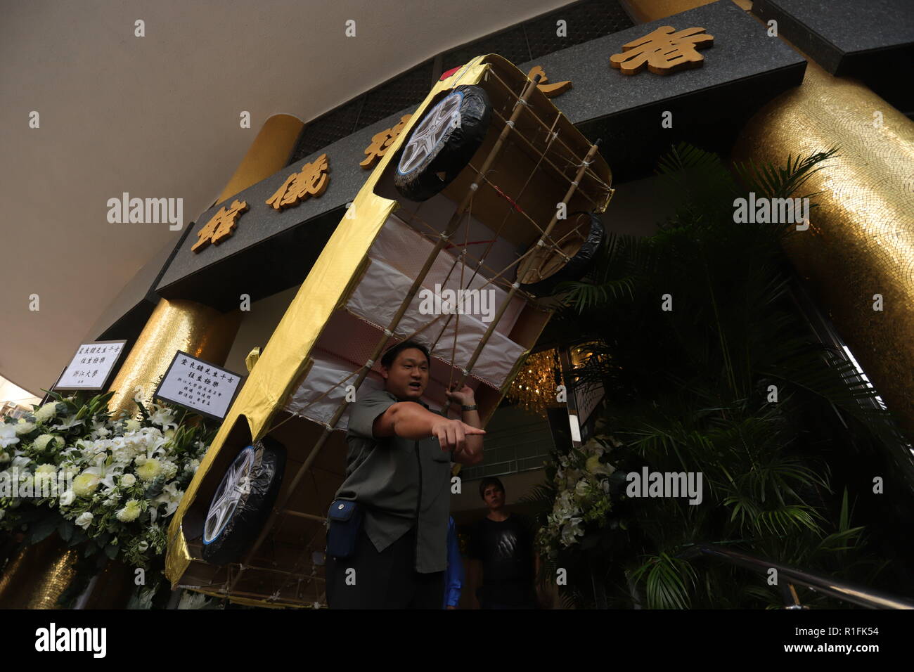 Hong Kong. 12 Nov, 2018. El hombre lleva un papel artesanal 'coche', un chino tradicional ofrendas para el difunto novelista Wuxia de Hong Kong, Jin Yong edad ( 94 ) fuera de la funeraria durante el servicio memorial.Nov-12 de 2018, Hong Kong.ZUMA/Liau Chung-ren Crédito: Liau Chung-ren/Zuma alambre/Alamy Live News Foto de stock