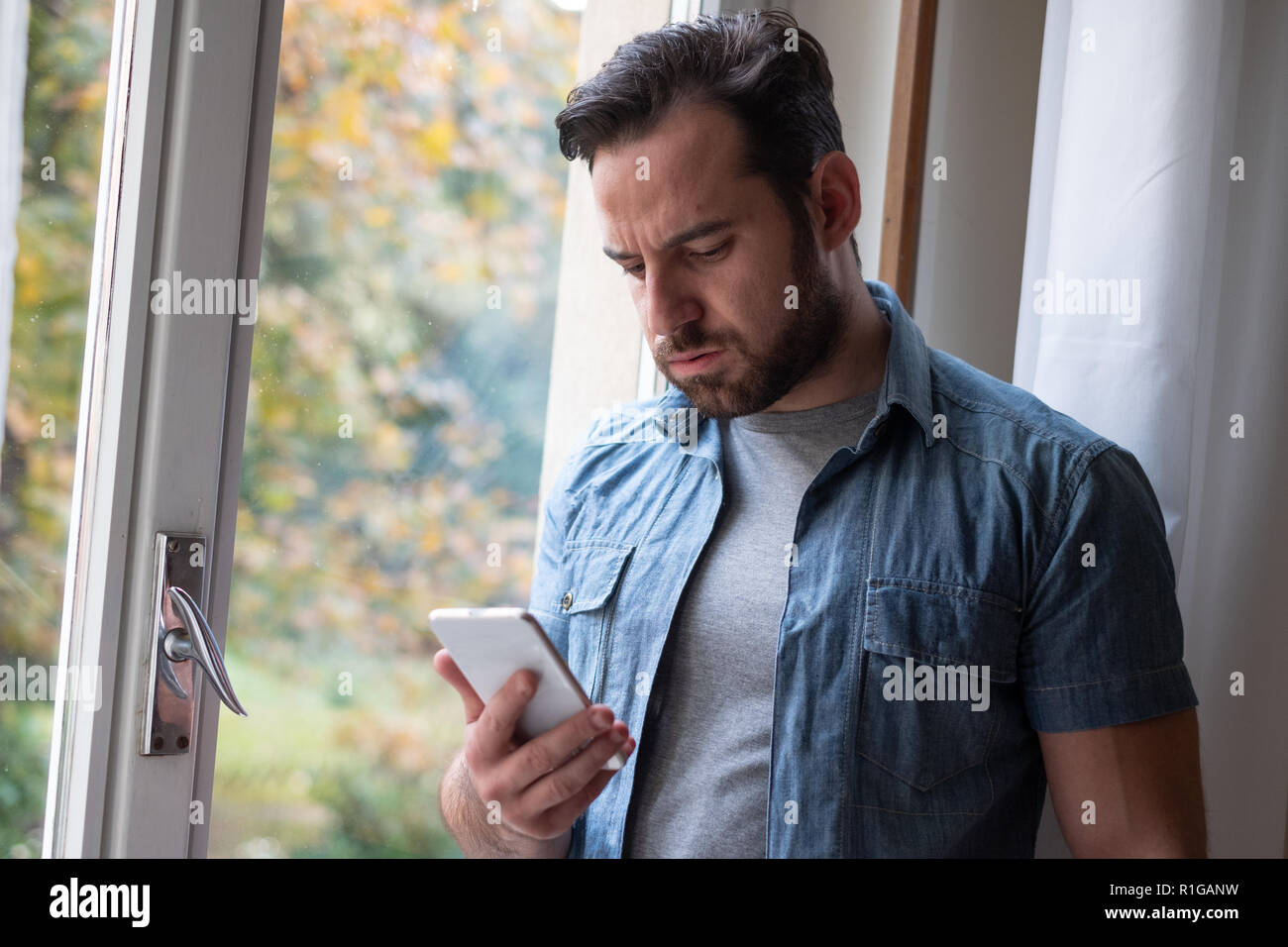 Preocupado hombre viendo smartphone y mensaje en espera Foto de stock