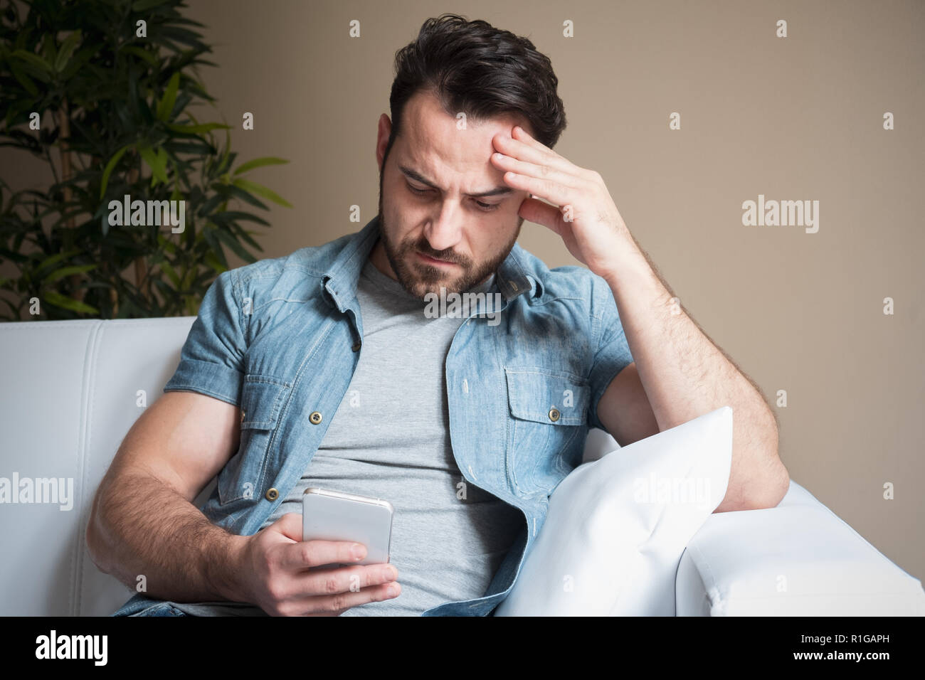 Un hombre preocupado viendo celular en casa Foto de stock