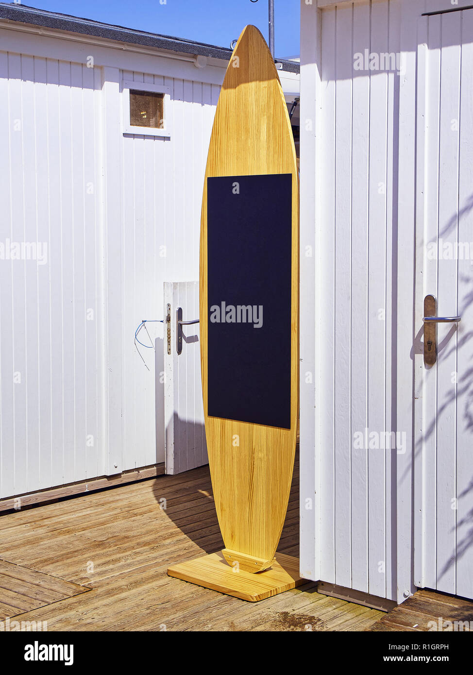 Una pizarra en forma de tabla de surf en una playa blanca cabinas. Foto de stock
