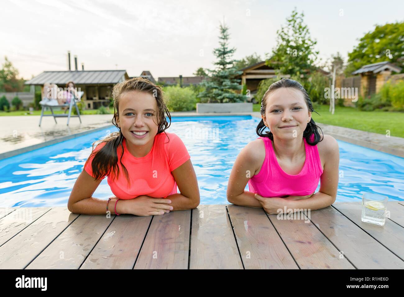 Dos jóvenes adolescentes divirtiéndose en la piscina, sonriendo mirando a la cámara. Foto de stock