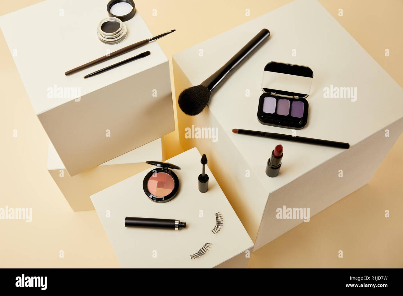 Un alto ángulo de visualización de diversos accesorios para maquillaje en cubos de color beige Foto de stock
