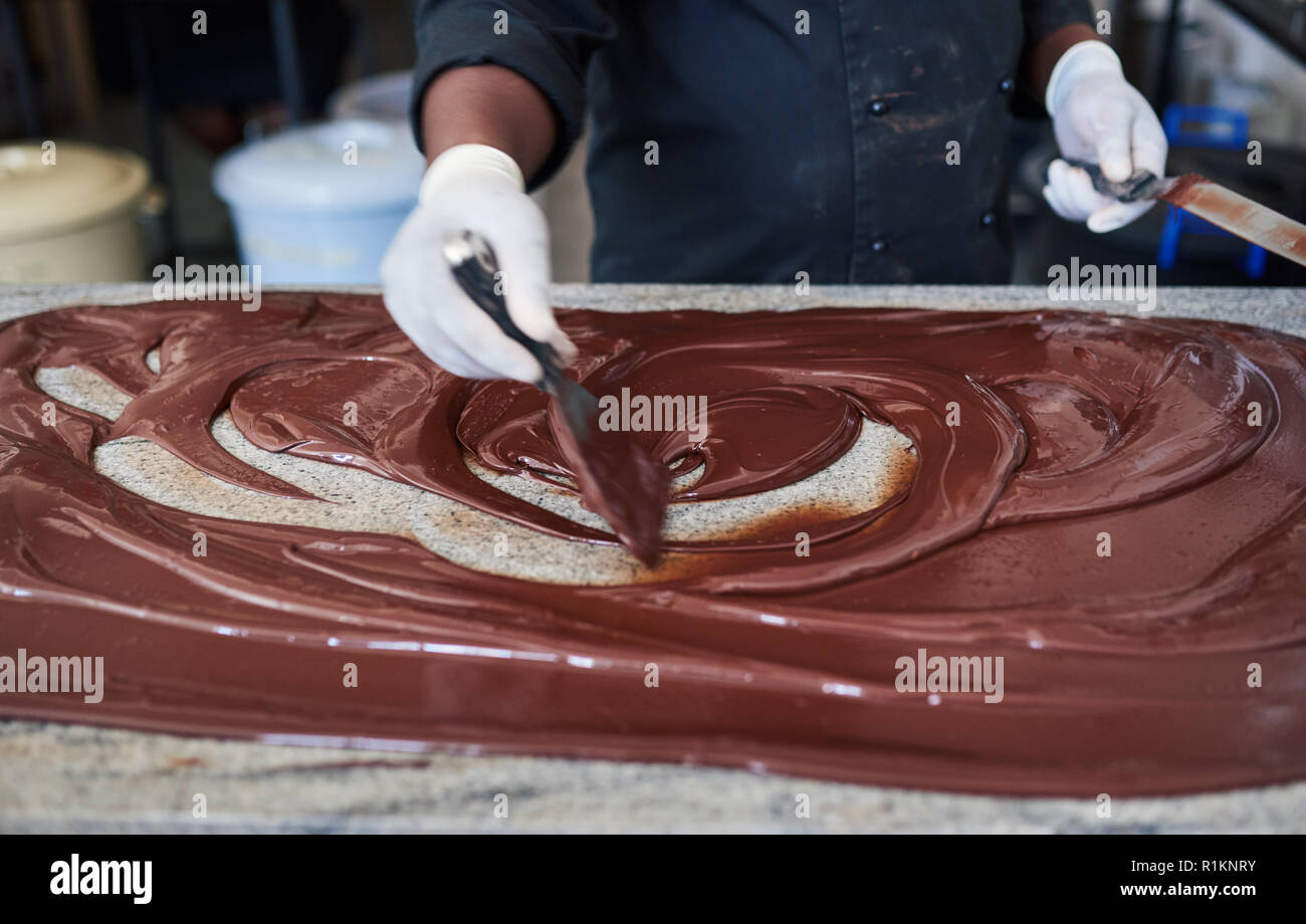 La mezcla de chocolate con espátulas de trabajador en un cuadro de fábrica Foto de stock