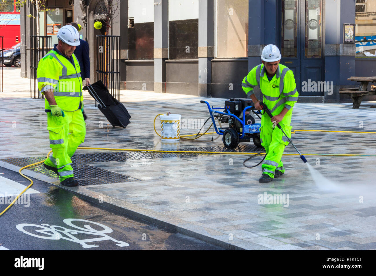 Limpiadores de calle con mangueras de presión en la plaza 'navegador', quitar la goma de mascar desde el nuevo centro peatonal de Arco, en el norte de Londres, Reino Unido Foto de stock