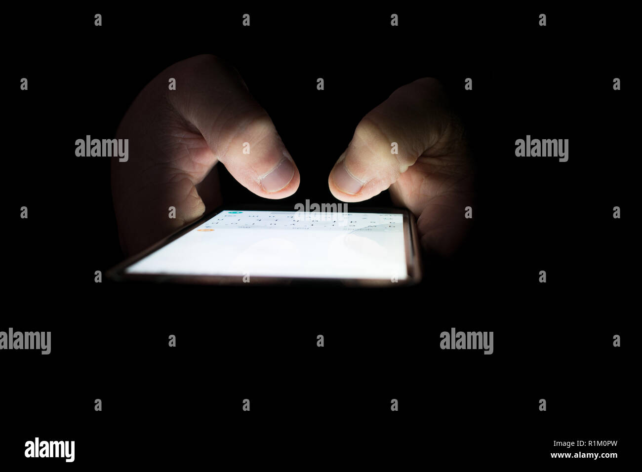 Dedos tocando la pantalla del smartphone con la luz apagada. Foto de stock