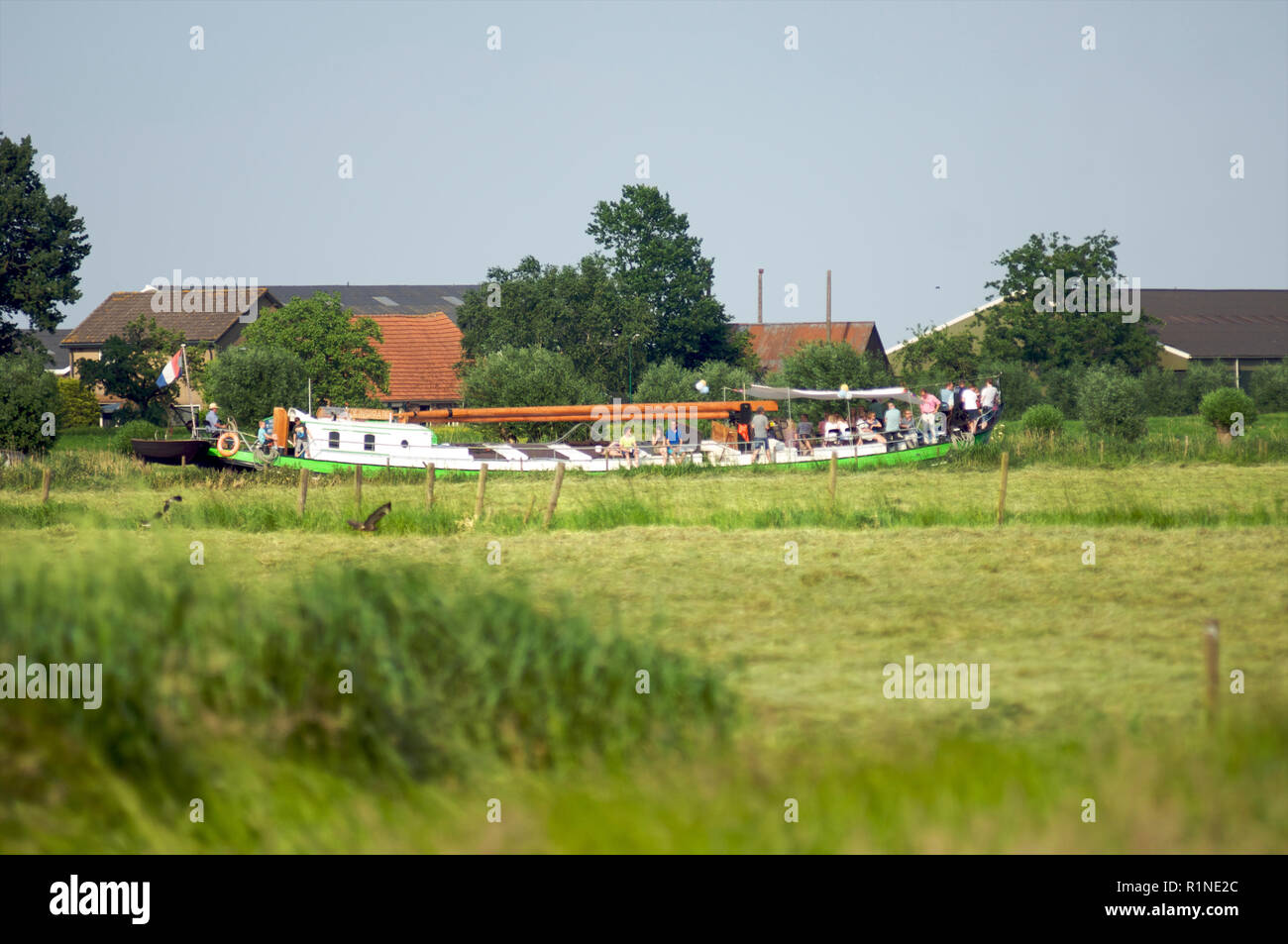 Un grupo de personas que viajaban en un bote a motor por el canal de Eem entre prados y casas de labranza, Países Bajos Foto de stock