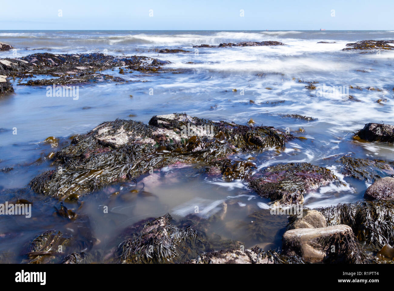 Playa rocosa de las ondas acuáticas con el Obturador lento el desenfoque de movimiento Foto de stock