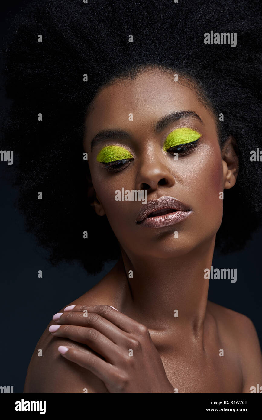 Retrato de hermosa modelo americano africano con neón brillante maquillaje  y hombros desnudos aislados en negro Fotografía de stock - Alamy