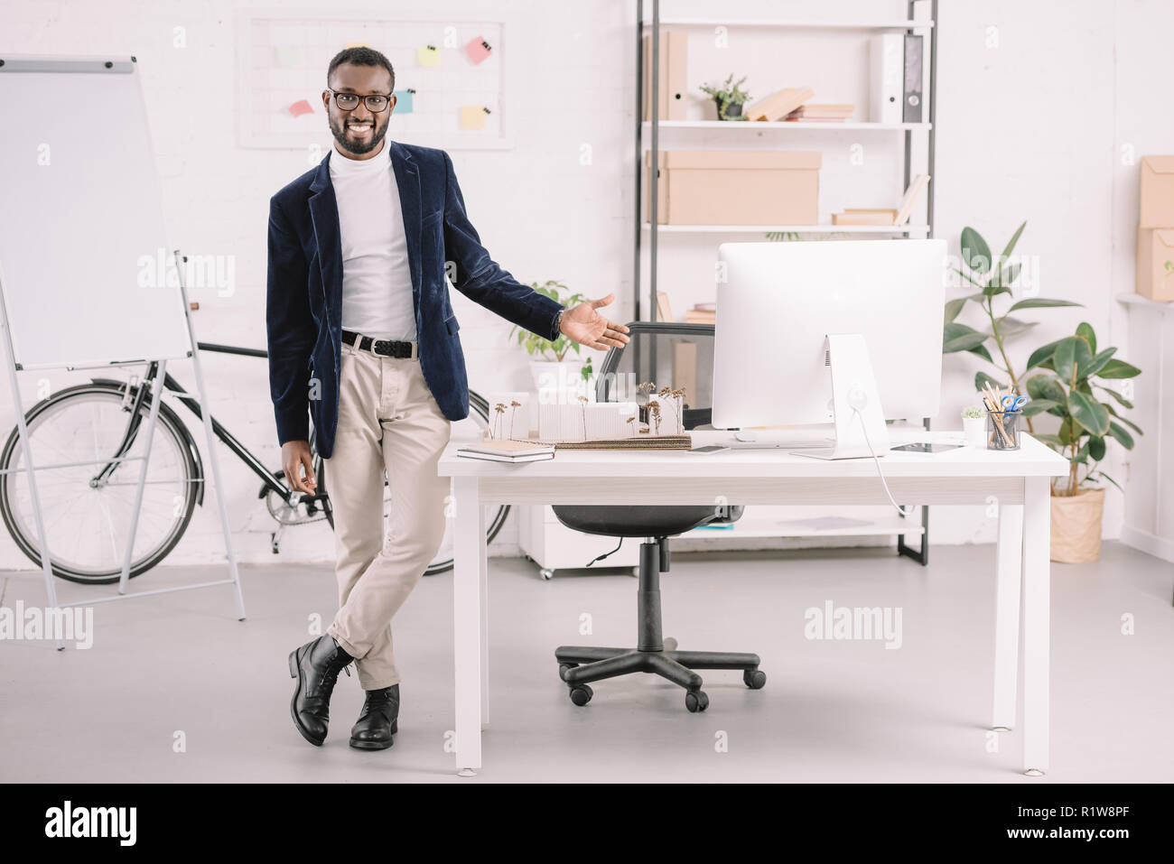 El arquitecto americano africano sonriente trabaja con modelo de edificios comerciales en la oficina con ordenador Foto de stock