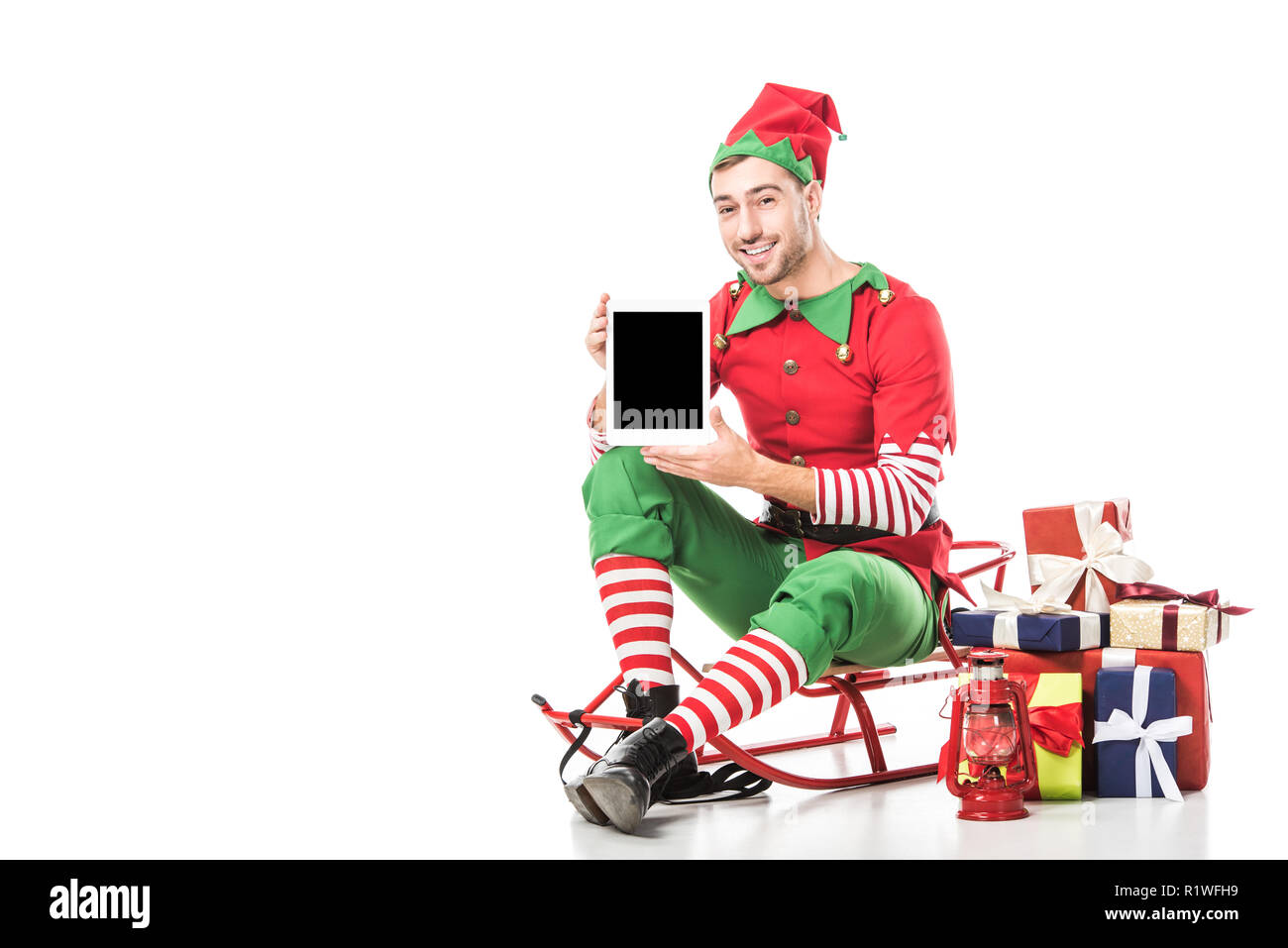 Hombre en navidad disfraz elfo sentado en trineo y celebración tablet con  pantalla en blanco aislado en blanco Fotografía de stock - Alamy