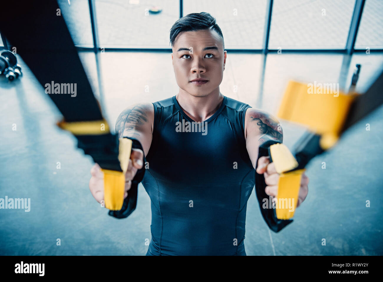Centrado joven deportista entrenamiento muscular con bandas de resistencia en el gimnasio Foto de stock