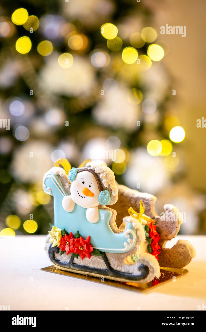 Gingerbread trineo con muñeco de nieve en la parte delantera de desenfoque luces de Navidad adornado abeto. Vacaciones dulces. Tema de Navidad y Año Nuevo. Mo festivo Foto de stock