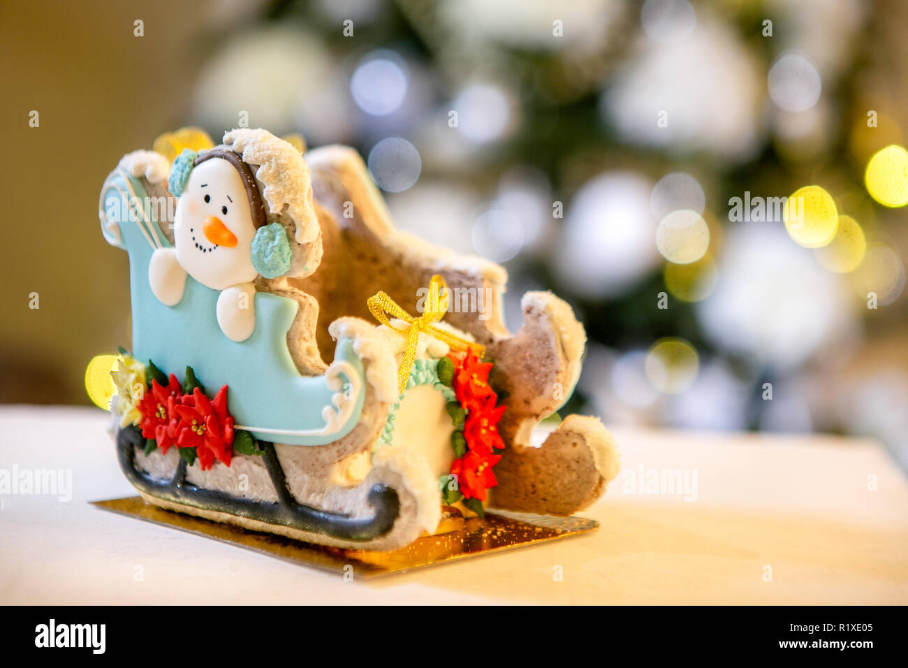 Gingerbread trineo con muñeco de nieve en la parte delantera de desenfoque luces de Navidad adornado abeto. Vacaciones dulces. Tema de Navidad y Año Nuevo. Mo festivo Foto de stock