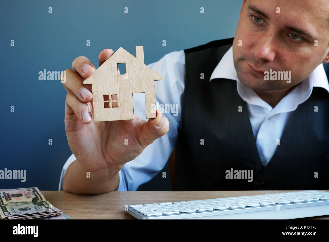Hombre sujetando el modelo de casa. La inversión inmobiliaria y la hipoteca de la casa. Foto de stock