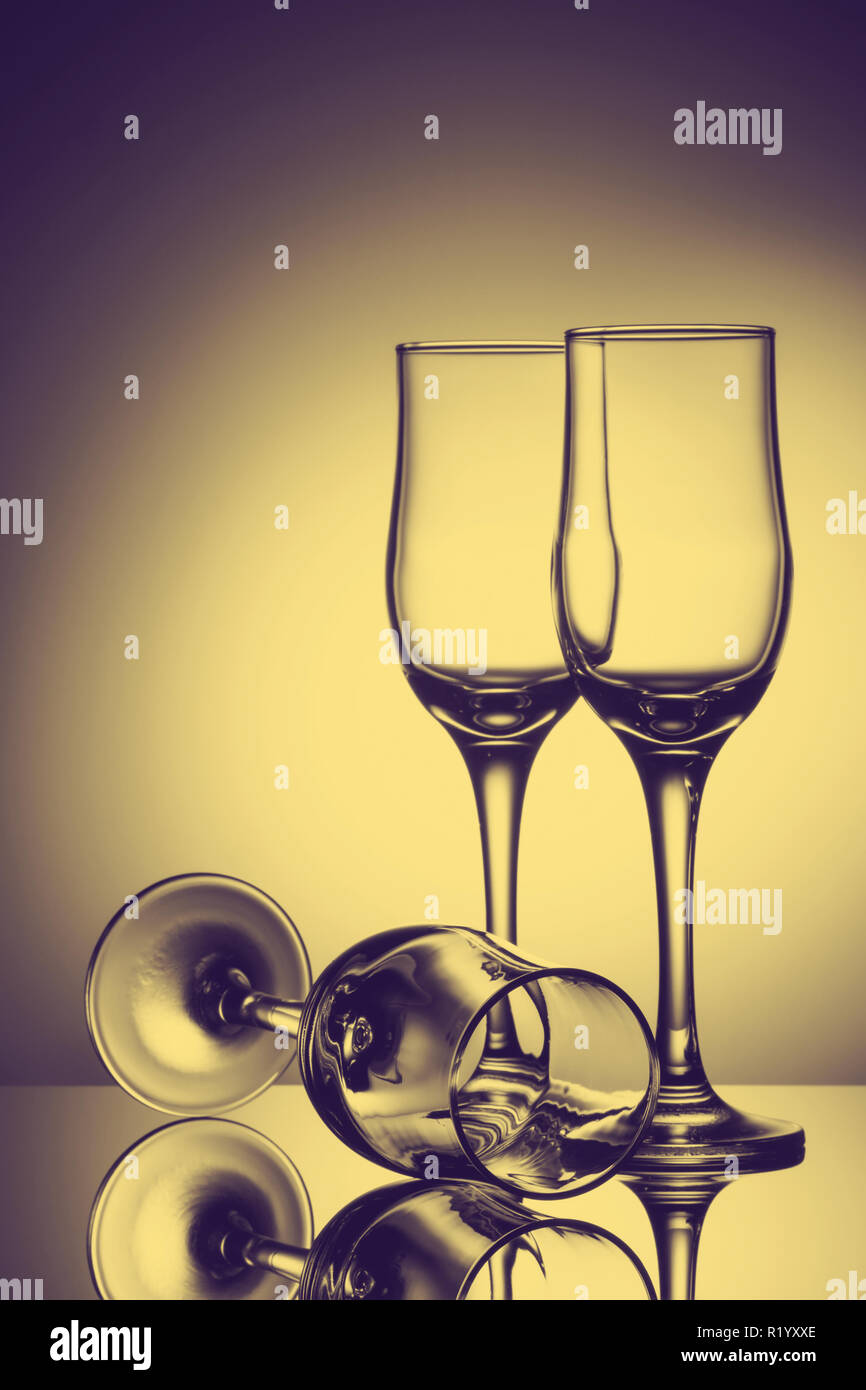 Tres copas de champaña vacía sobre fondo de color con la reflexión. Imagen publicitaria de tonos de arte Foto de stock