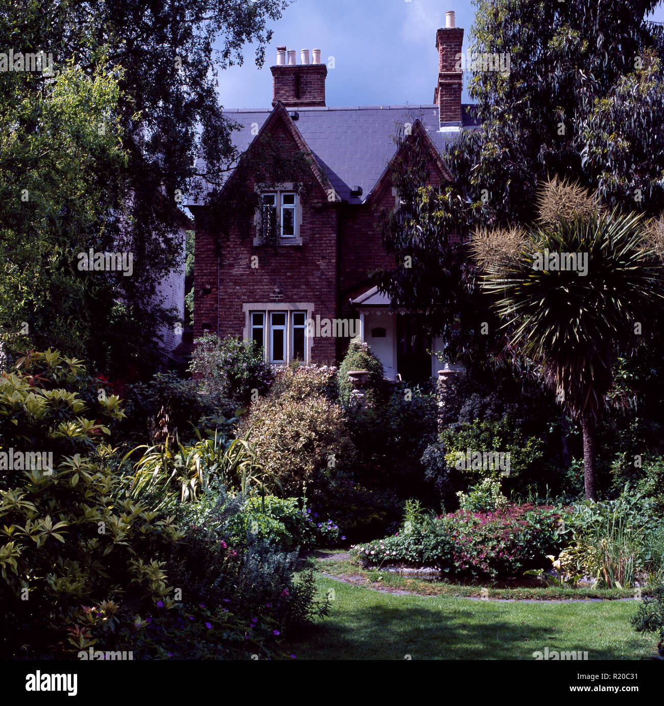 Palmeras y arbustos verdes en el jardín de la gran casa victoriana Foto de stock