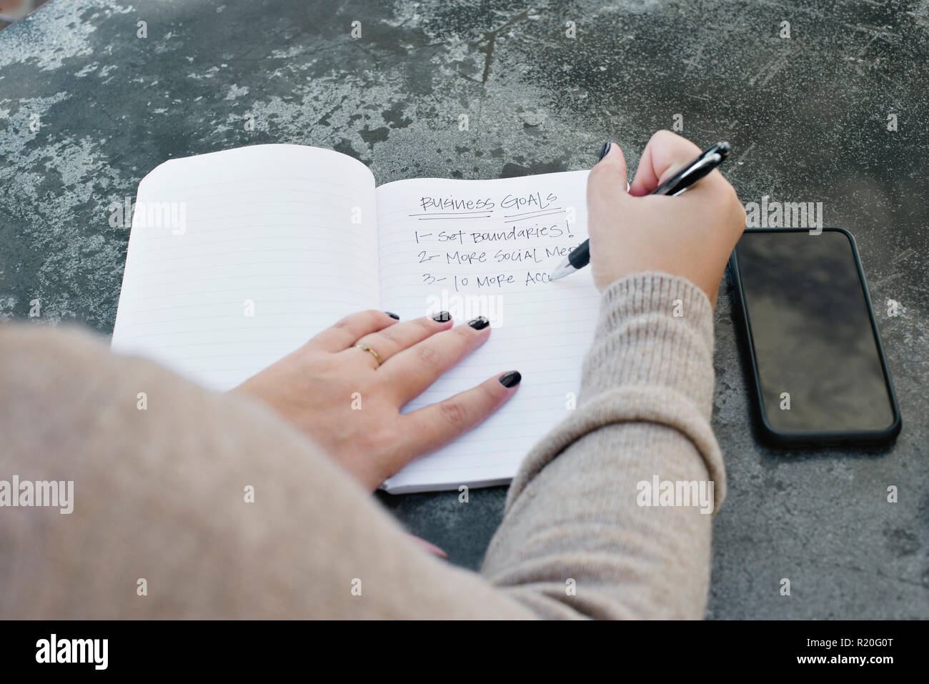 Una mujer escribe sus objetivos de negocio para el año que viene Foto de stock