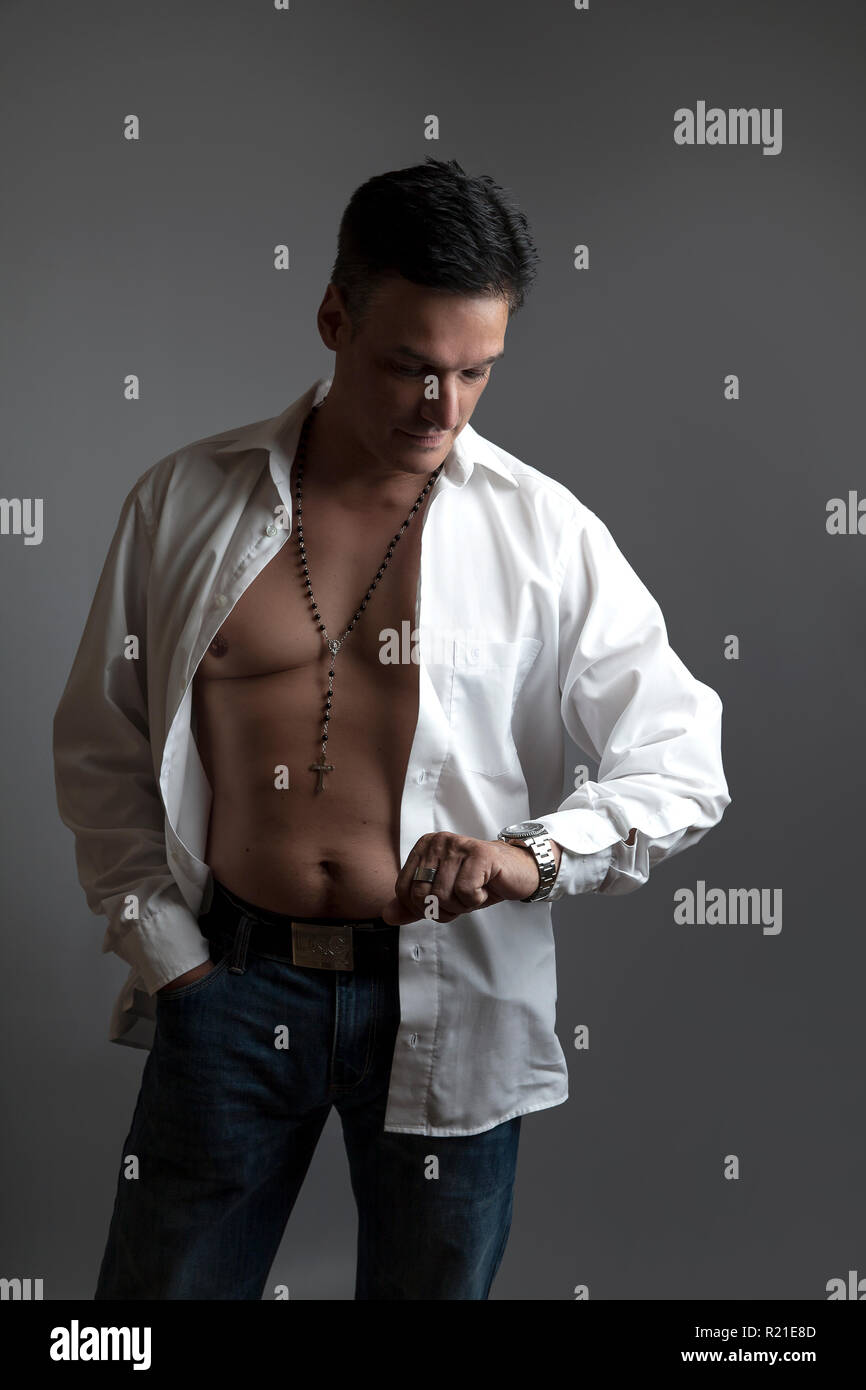 Apuesto hombre sexy en una camisa blanca posando en el studio Foto de stock