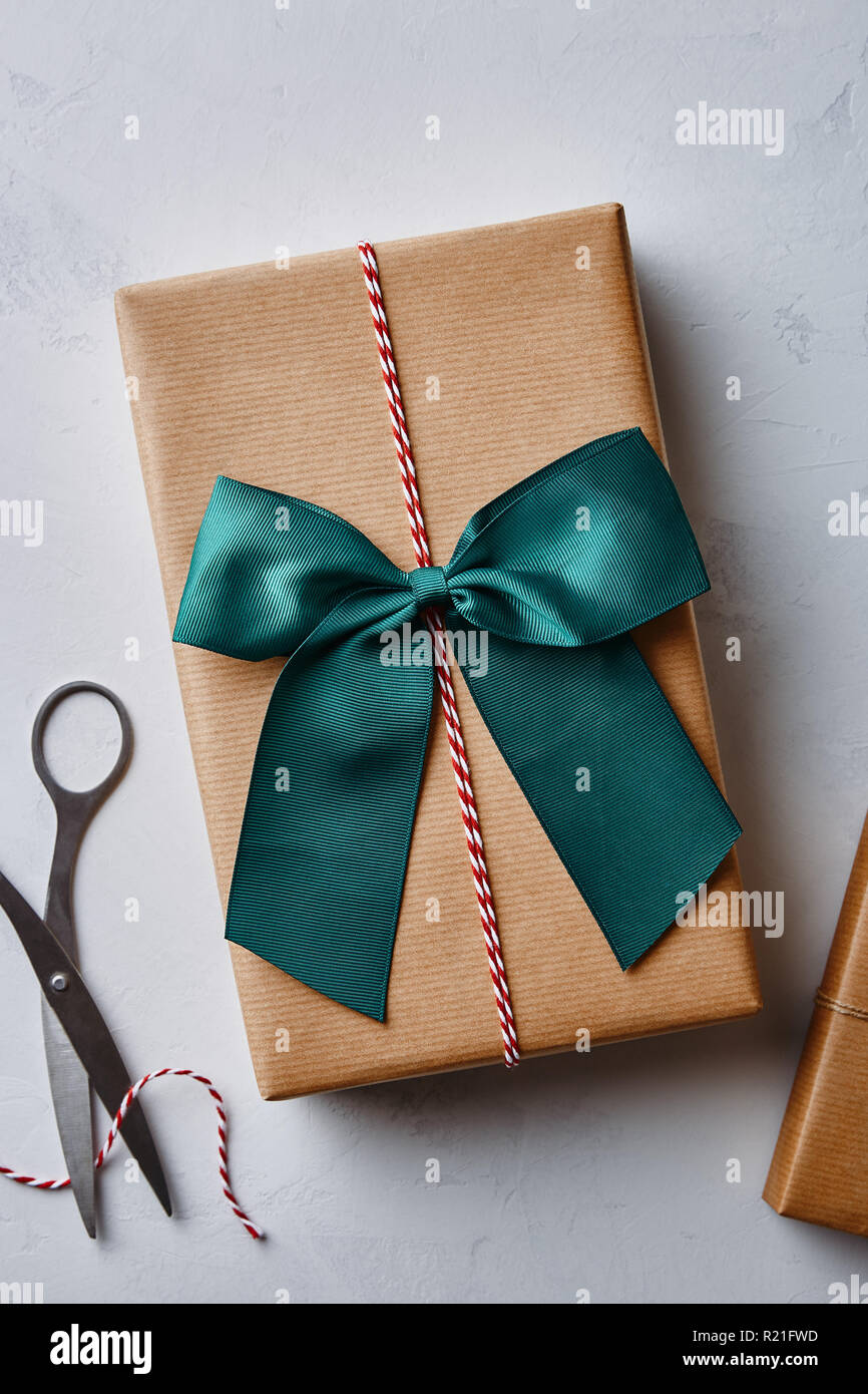 Regalo de navidad envuelto en papel marrón con cordel, arco y unas tijeras. Vista desde arriba Foto de stock