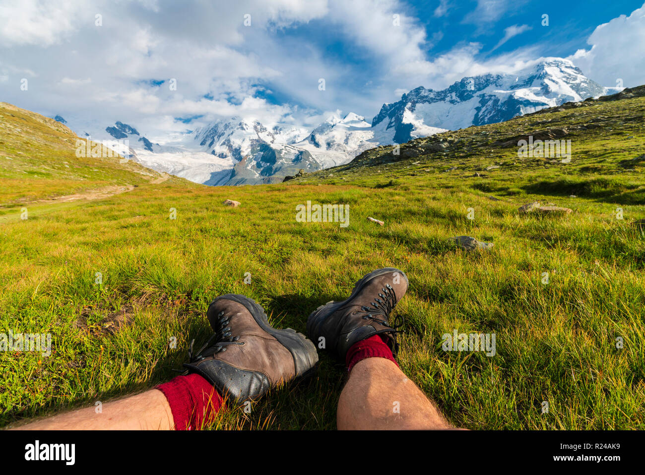 Excursionista descansa sobre la hierba mirando hacia el macizo del Monte Rosa, Riffelalp, Zermatt, cantón de Valais, Suiza Alpes, Suiza, Europa Foto de stock