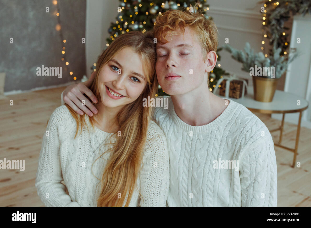 Hermosa joven pareja sentados juntos y sonrientes en la cámara en la víspera de Navidad Foto de stock