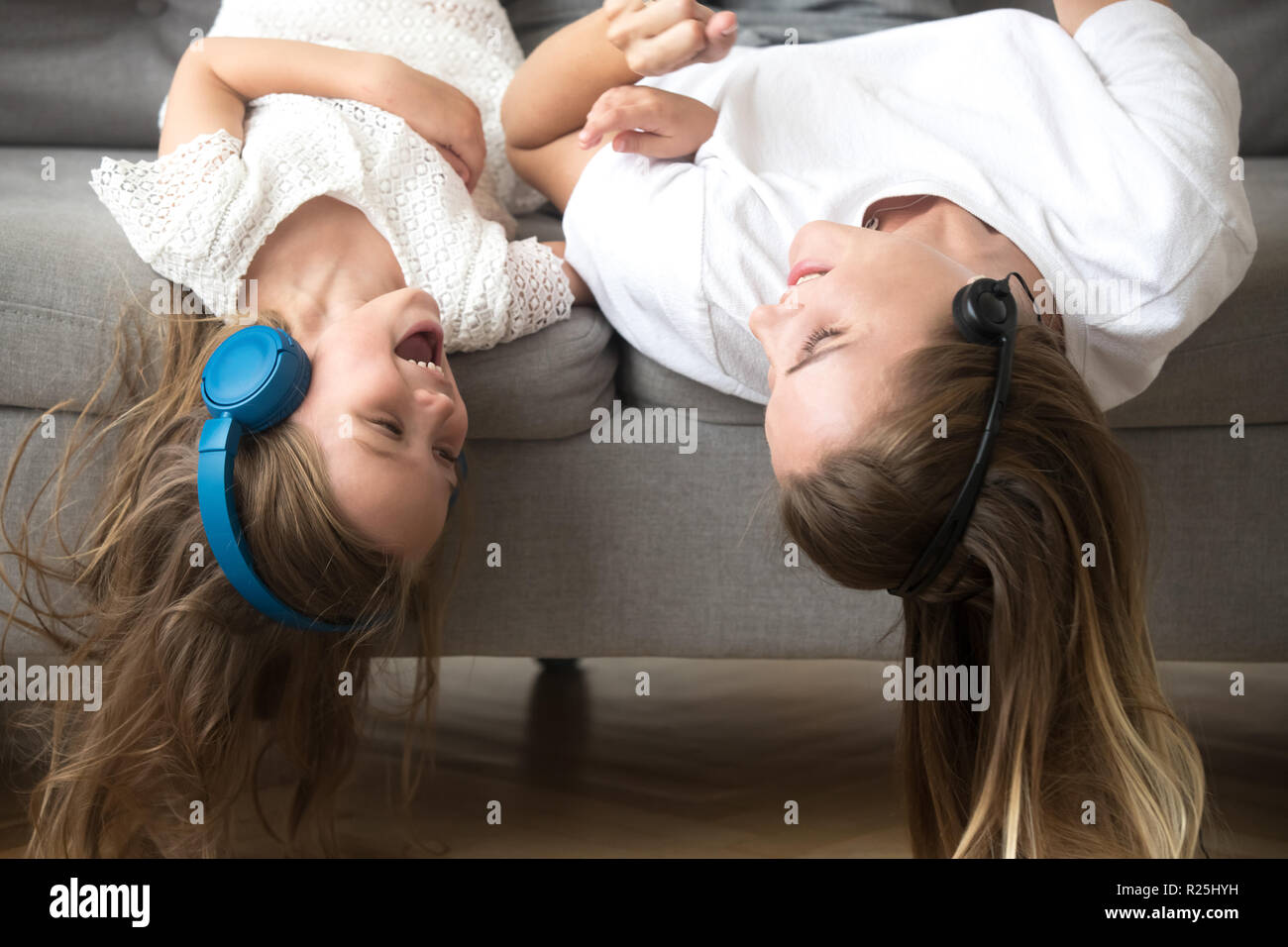 Kid y madre recostada boca abajo en auriculares para disfrutar de la música Foto de stock